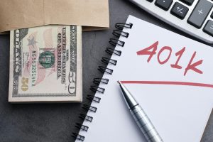dollar bills spilling from an envelope next to a calculator and a notepad with "401k" written on it